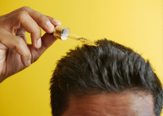 Mężczyzna nakłada na włosy olejek do włosów
