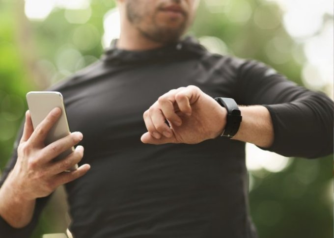 Mężczyzna w trakcie biegu sprawdza powiadomienia na sportowym smartwatchu męskim